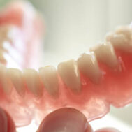 A pair of private dentures being held in hand.
